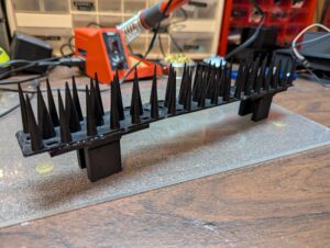 A plastic spike strip with two brackets glued onto the bottom