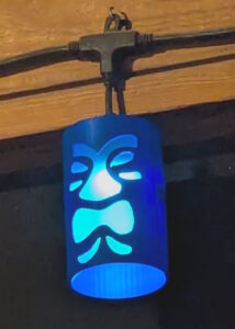 Blue tiki shade hung over one of the deck lights, with the light lit inside. 